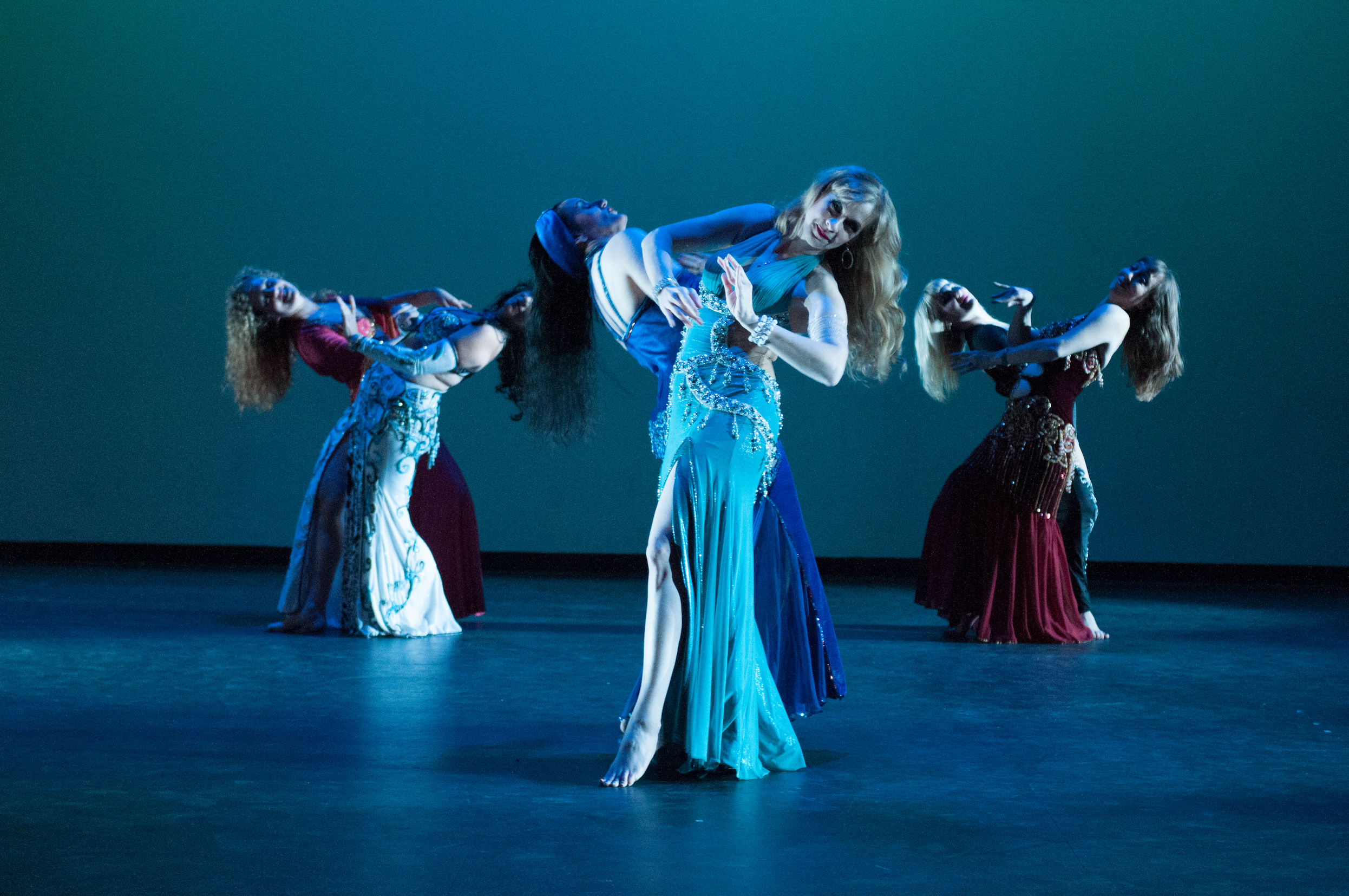Six belly dancers on stage, positioned in pairs