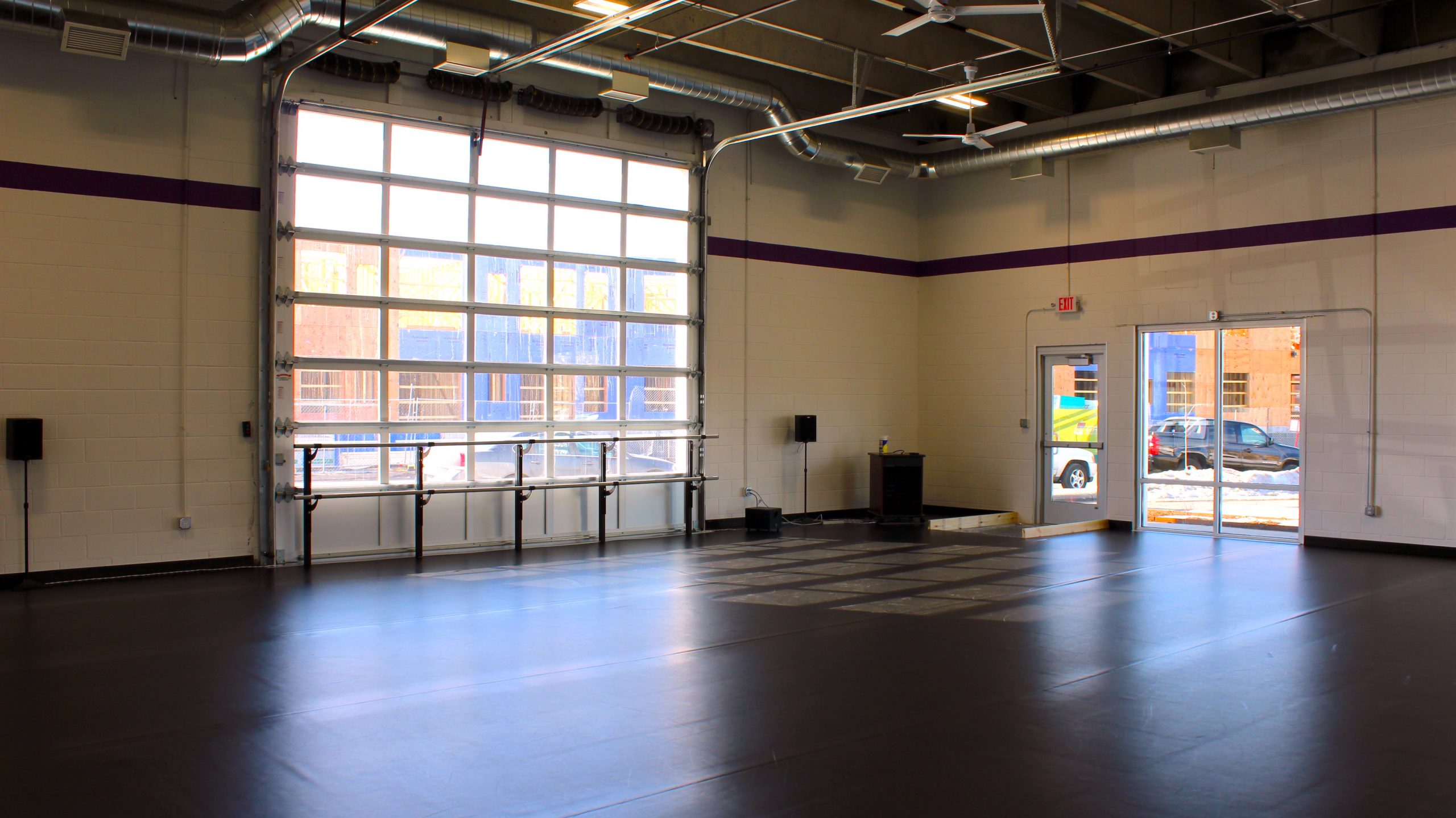 An image of the Nexus dance studio, with a wall of windows and black Marley floor