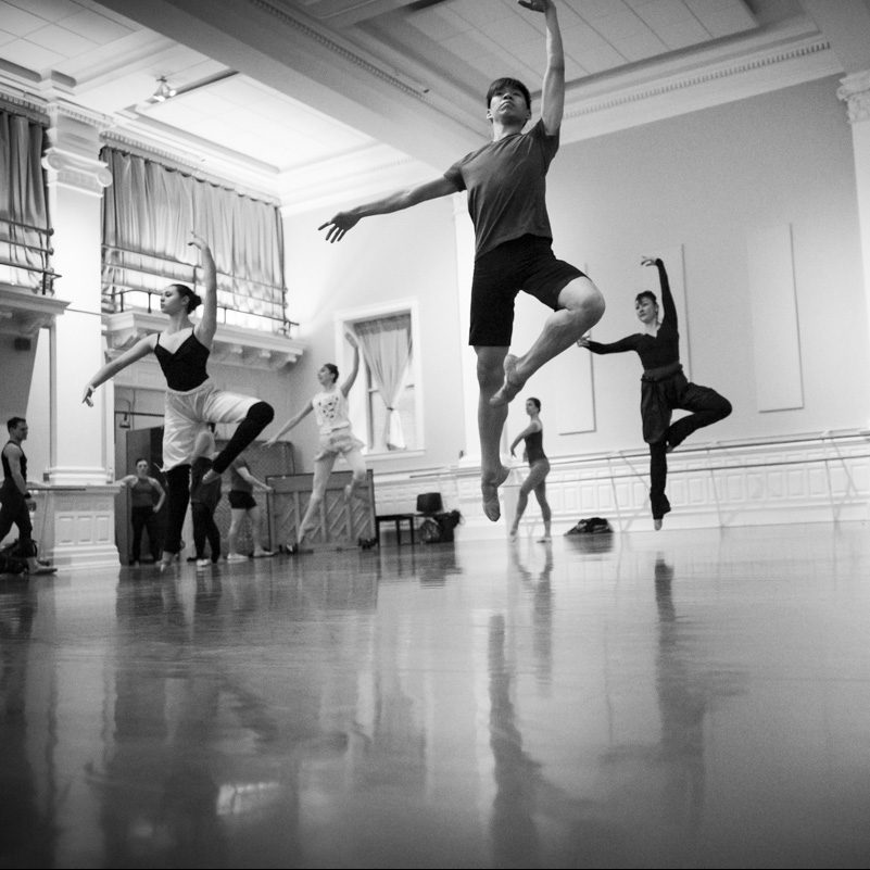 A group of ballet students jump with one leg in passe