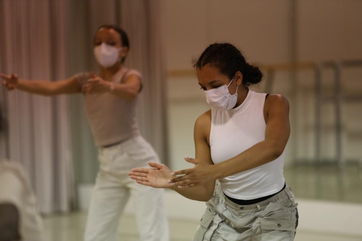 two dark-skinned dancers in masks dance in the main studio at TU Dance Center