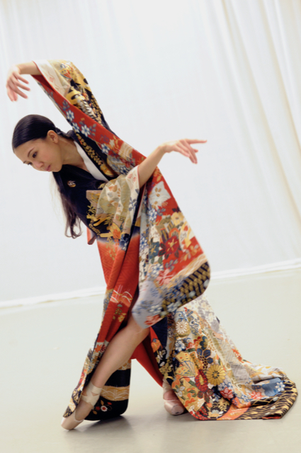 Yuki, a Japanese woman, is dressed in a Japanese robe and pointe shoes. She curves her body to the right