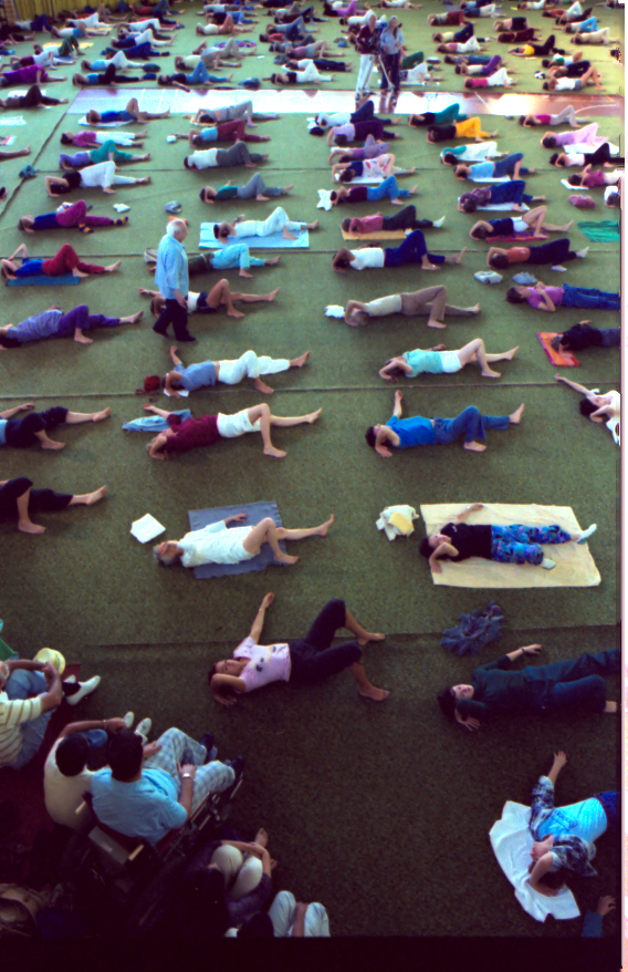 A large room filled with several people lying on mats in ordered rows