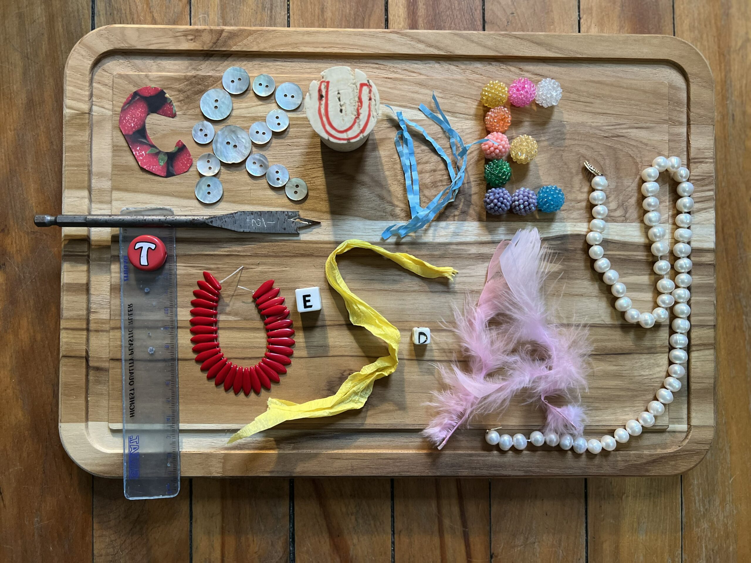 CRUDE TUESDAY spelled with yarn, button, and miscellaneous materials