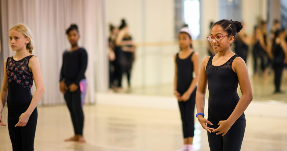 Several youth of different skin tones stand in the TU Dance Center studio